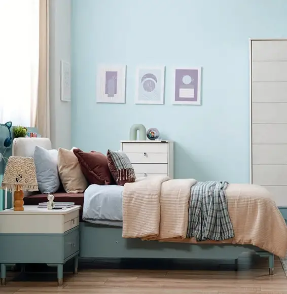 Ein von D-Lux eingerichtetes hellblaues Schlafzimmer mit einem Bett mit farbigen Decken und Kissen