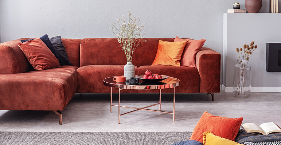 Rotes Samtsofa mit orangefarbenen Kissen und Beistelltisch in einem modernen Wohnraum