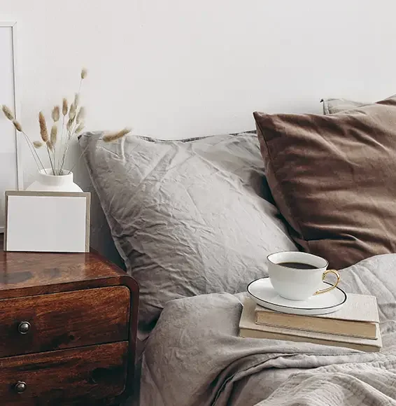 D-Lux Möbel – Textilien und Stoffe Braunes Samtkissen und graues Leinenkissen bilden einen Kontrast auf einem Bett