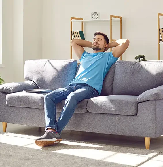 Ein junger Mann sitzt bequem auf seinem Sofa