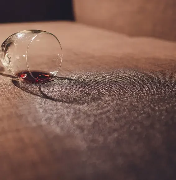 Ein umgefallenes Glas Wein auf einem Sofa