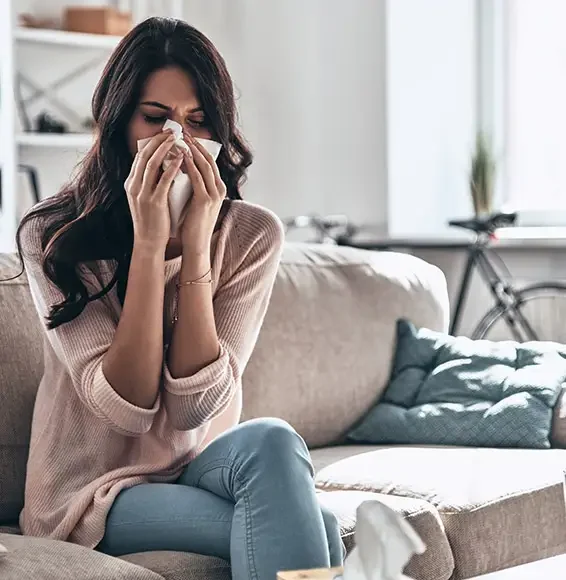 Eine Frau auf einer Couch putzt sich die Nase