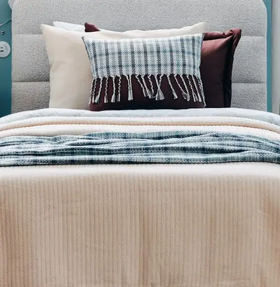 D-Lux Möbel – Textilien und Stoffe Kissen und Decken aus unterschiedlichen Stoffen und mit verschiedenen Mustern auf einem Bett