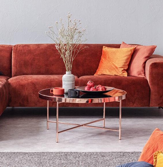 D-Lux Möbel Rotes Samtsofa mit orangefarbenen Kissen und Beistelltisch in einem modernen Wohnraum